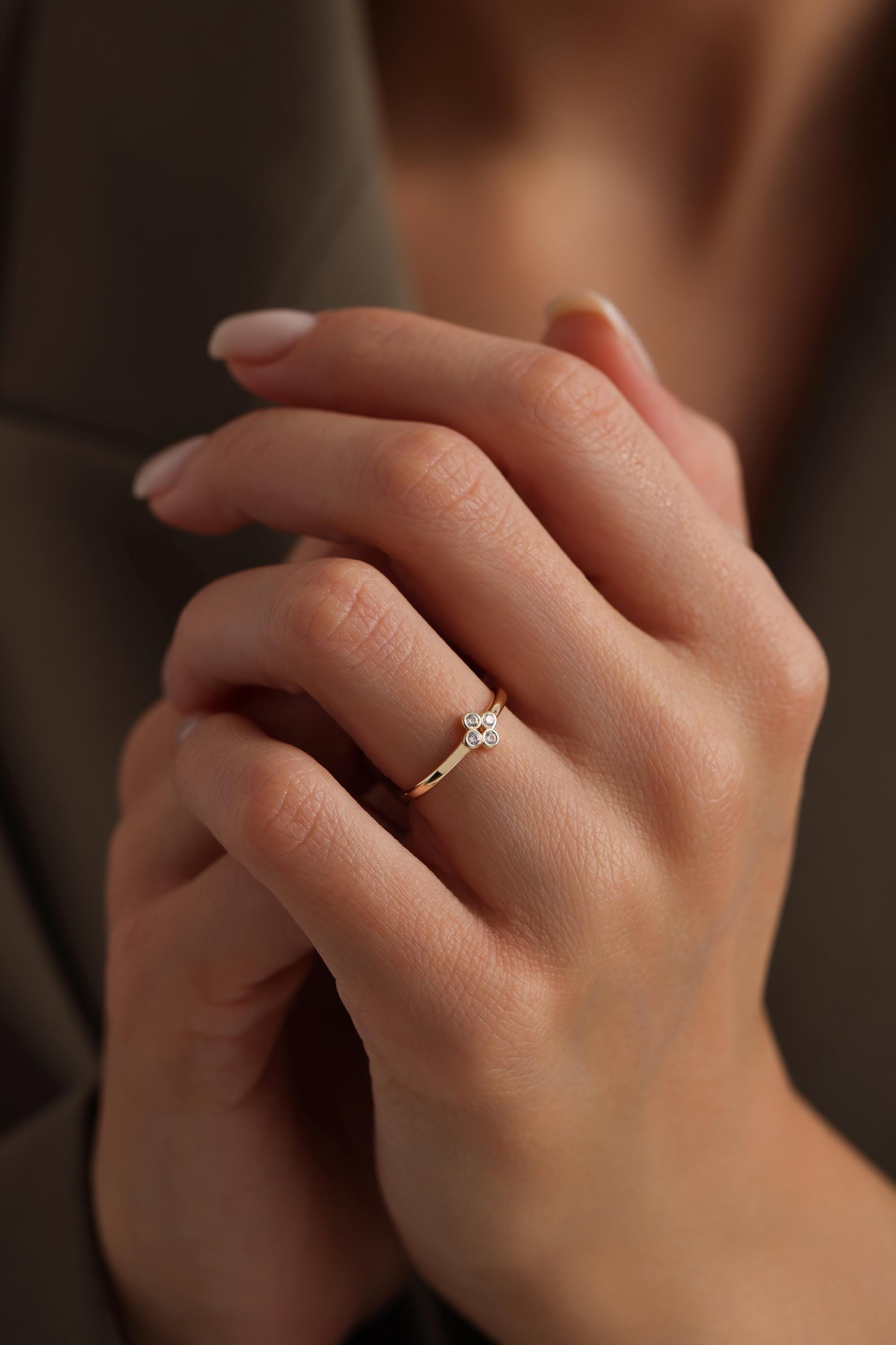 May include: A gold ring with a cluster of five small round diamonds set in the center.