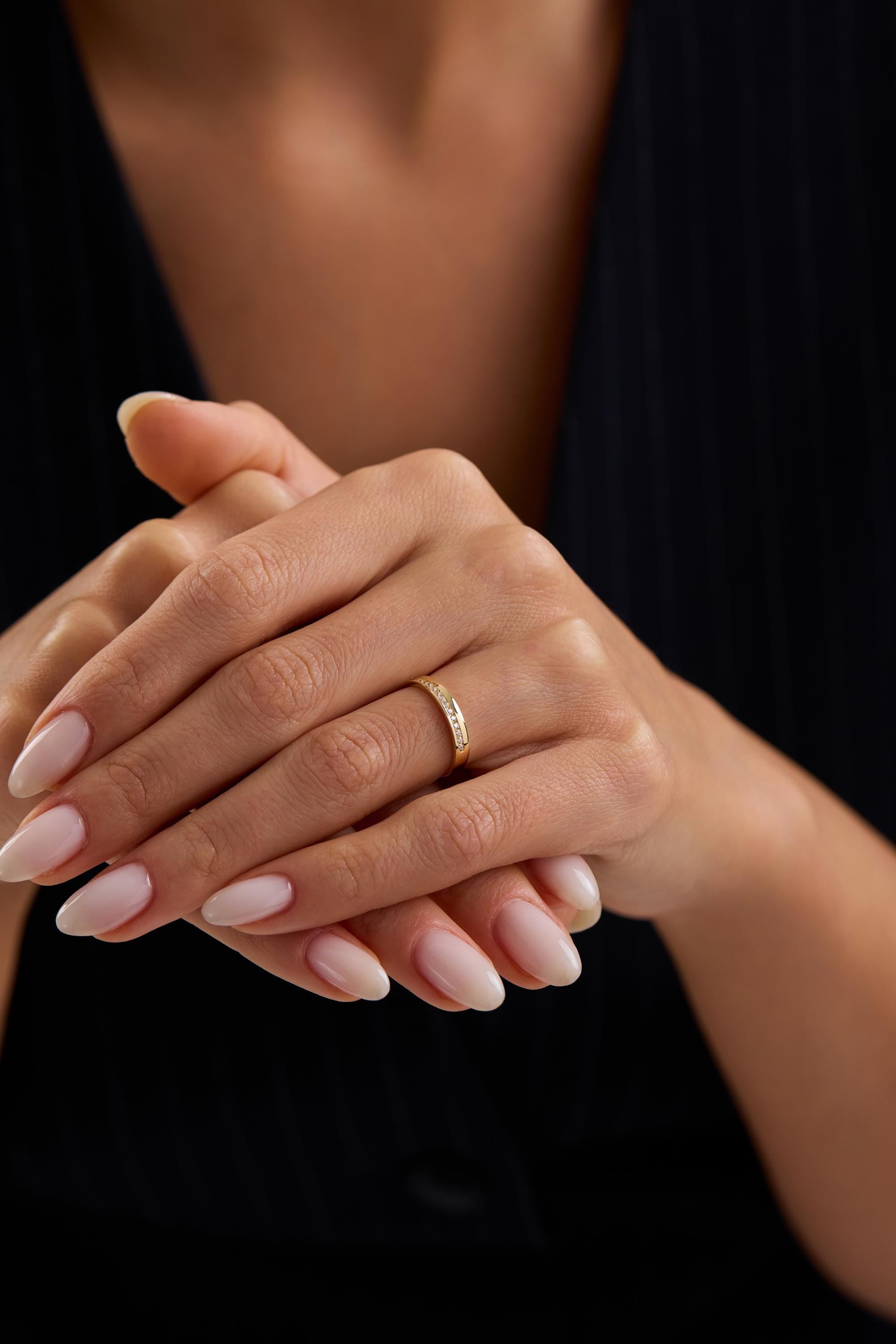 A close-up image of a person's hands wearing a gold ring.