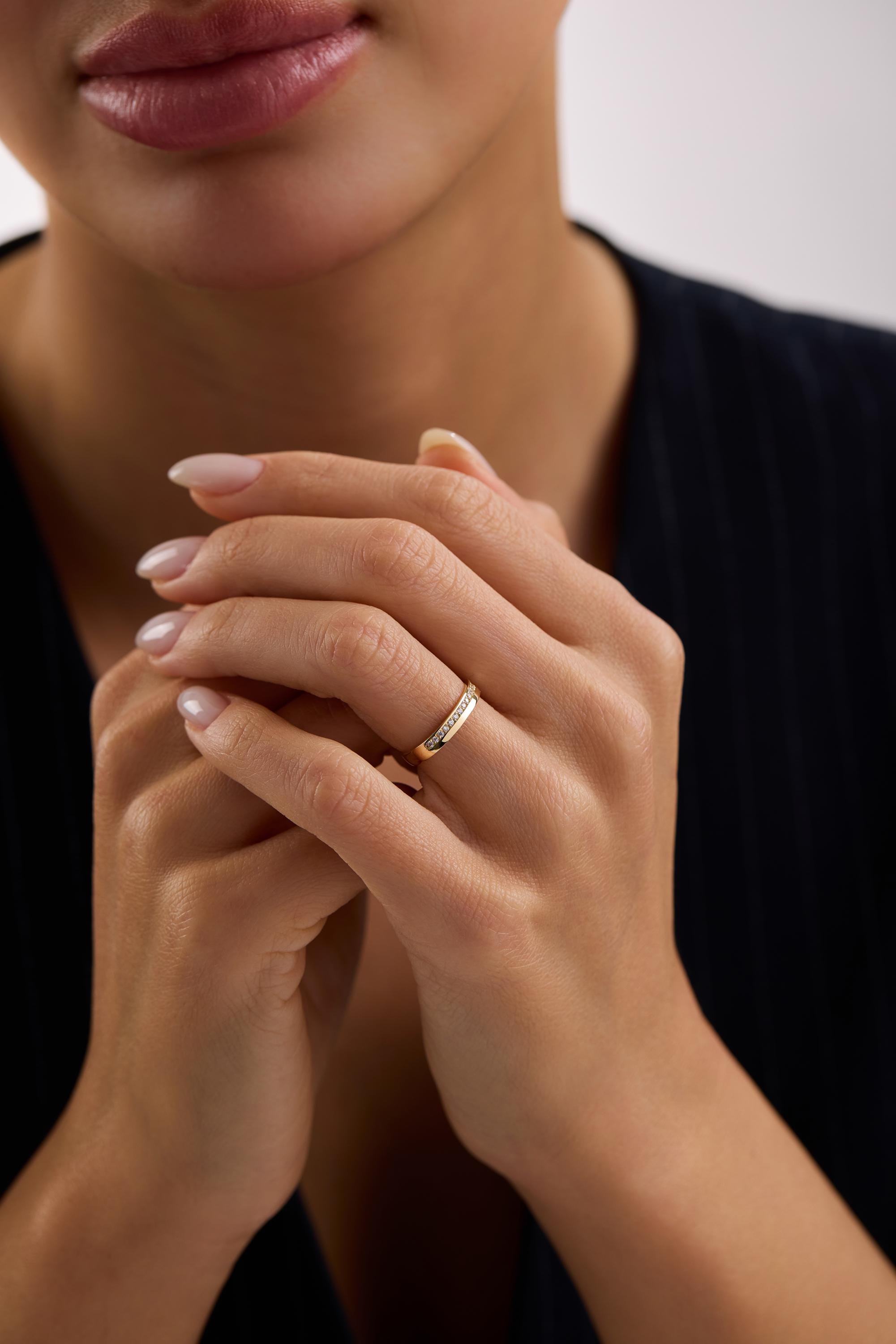 A close-up of a person's hands wearing a gold ring, with their fingers crossed.