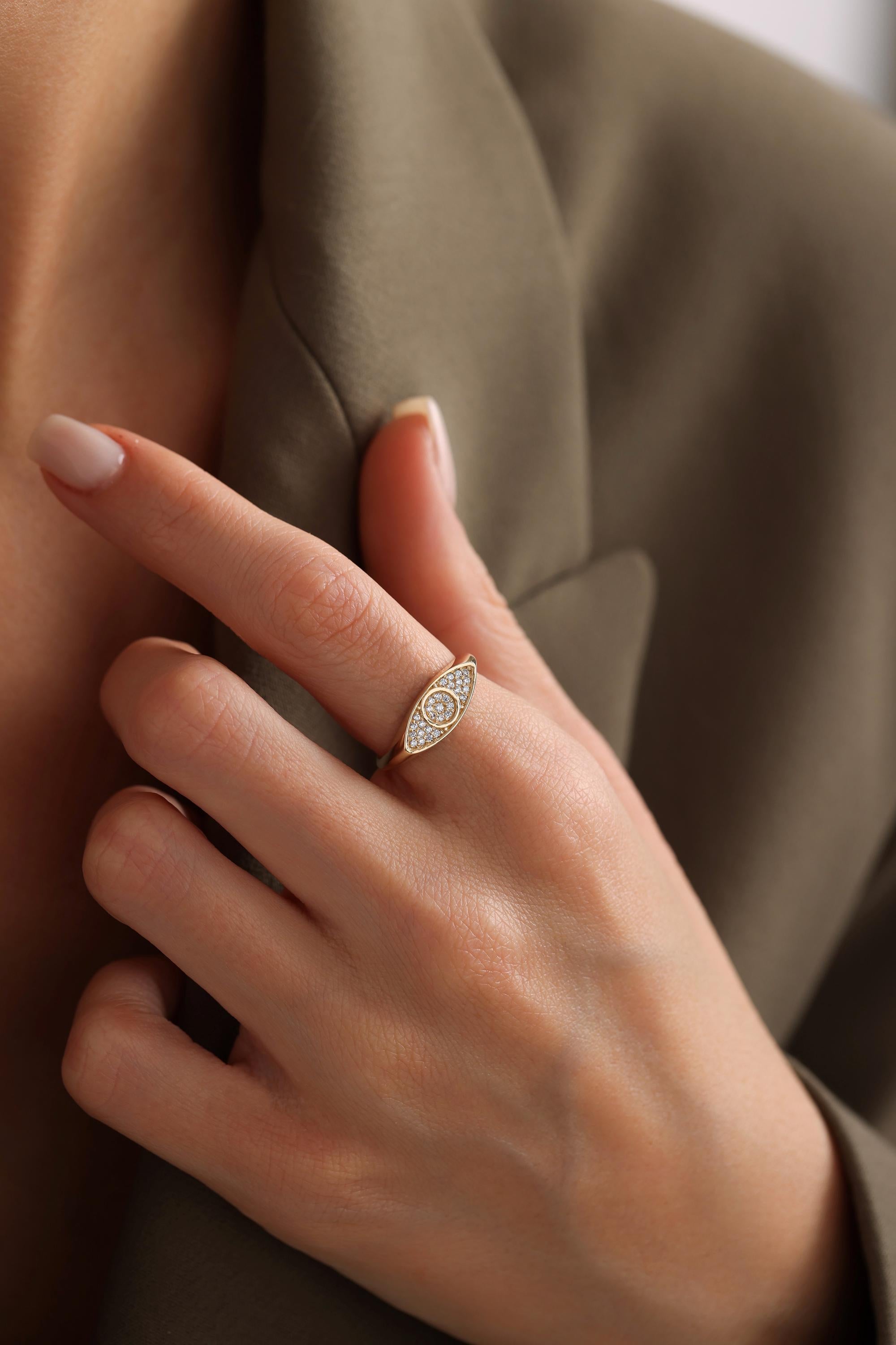 A close-up of a person's hand wearing a gold ring with a diamond-like design.