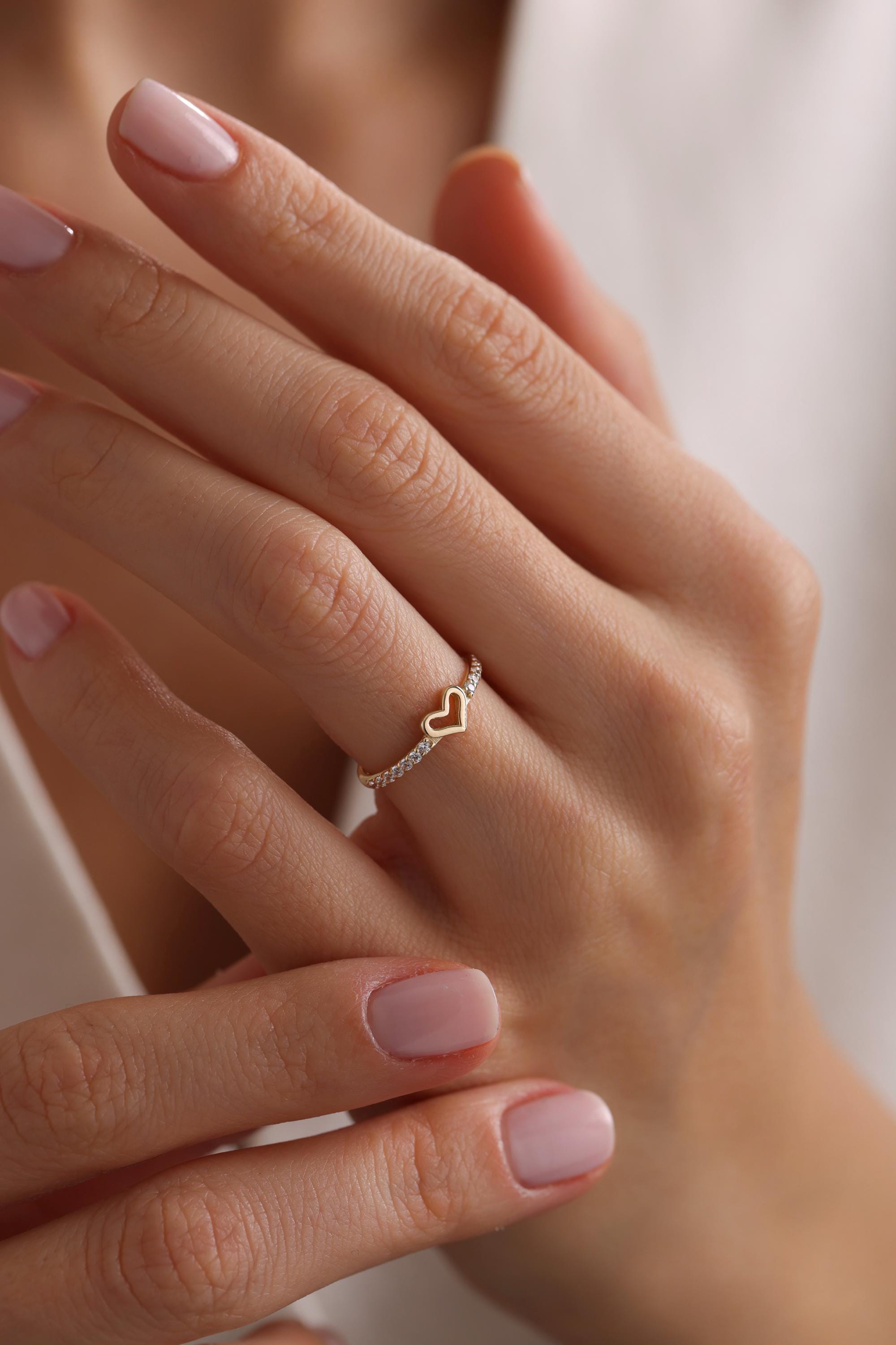 May include: A gold ring with a heart-shaped design and small clear stones around the band.