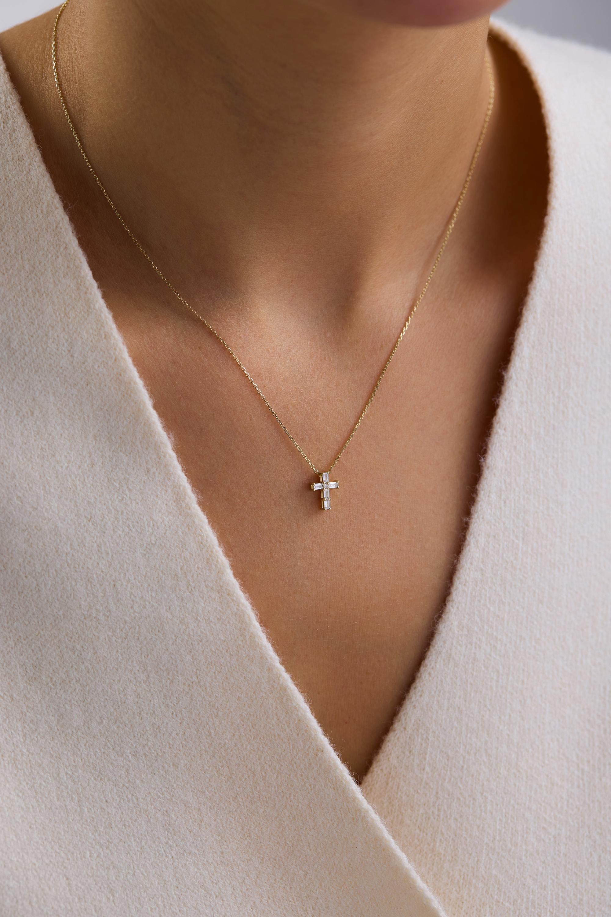 A close-up view of a person wearing a gold necklace with a small cross pendant.