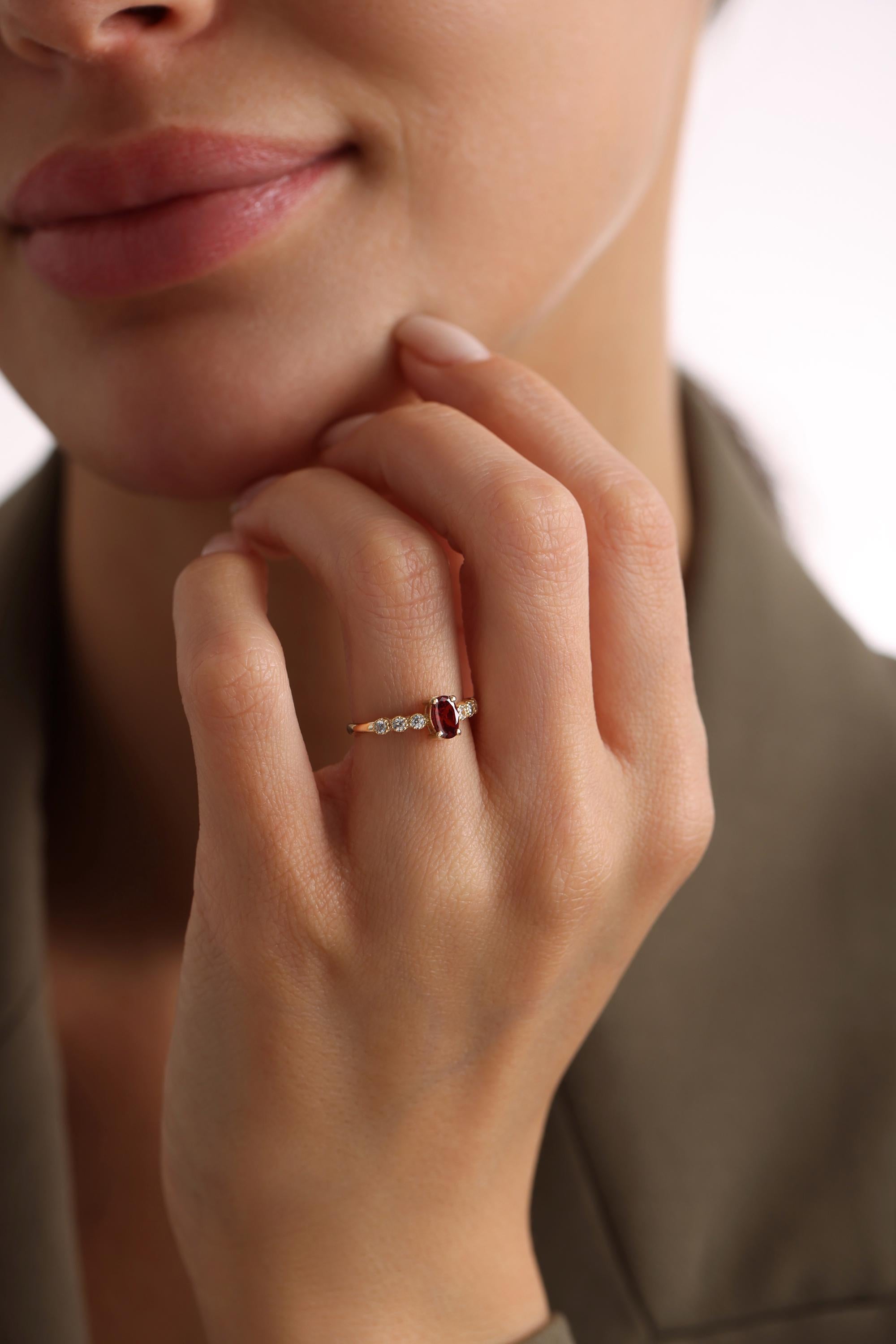 A close-up of a person's hand wearing a gold ring with a red gemstone, resting on their thumb.