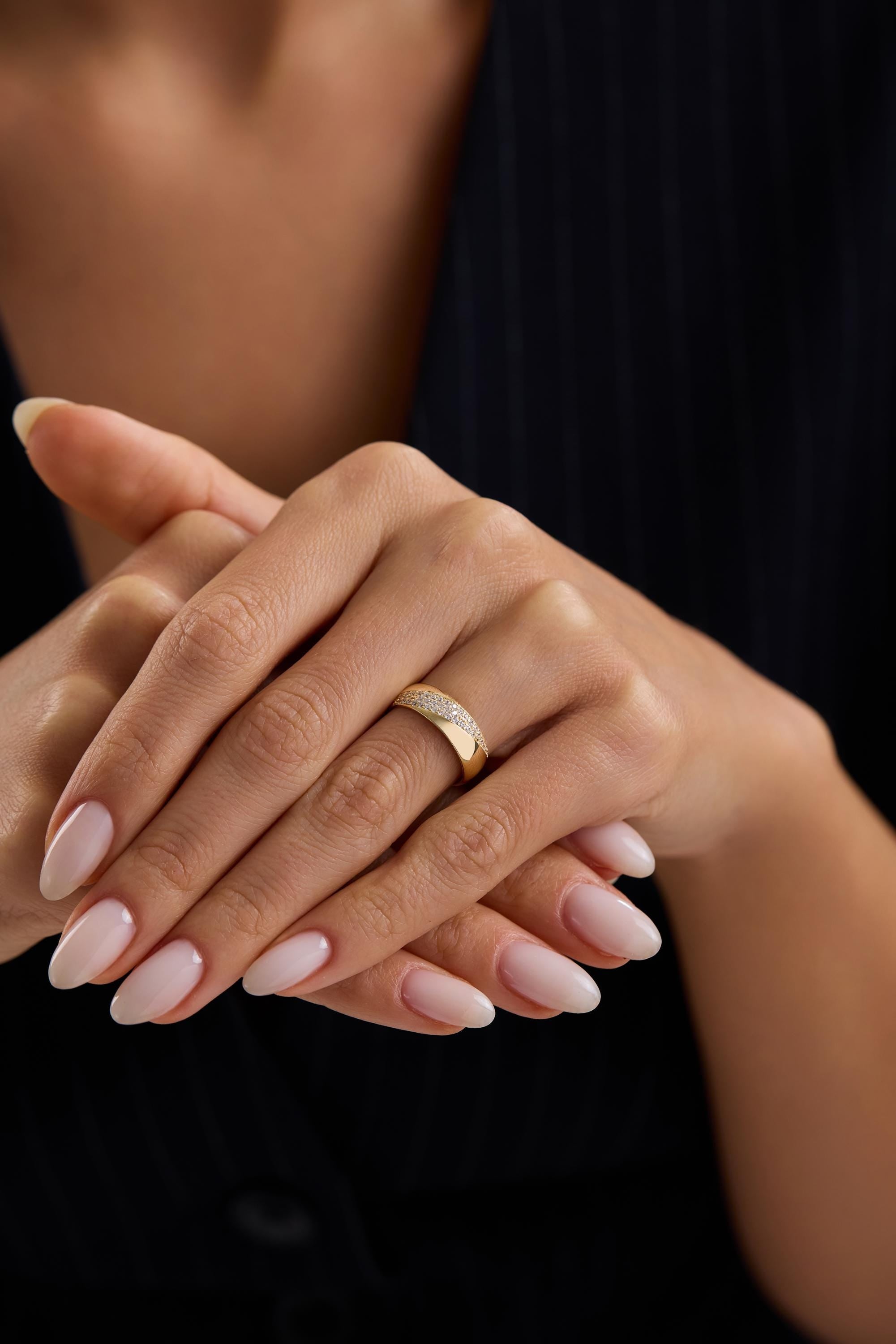 A close-up image of a person's hands wearing a gold ring.