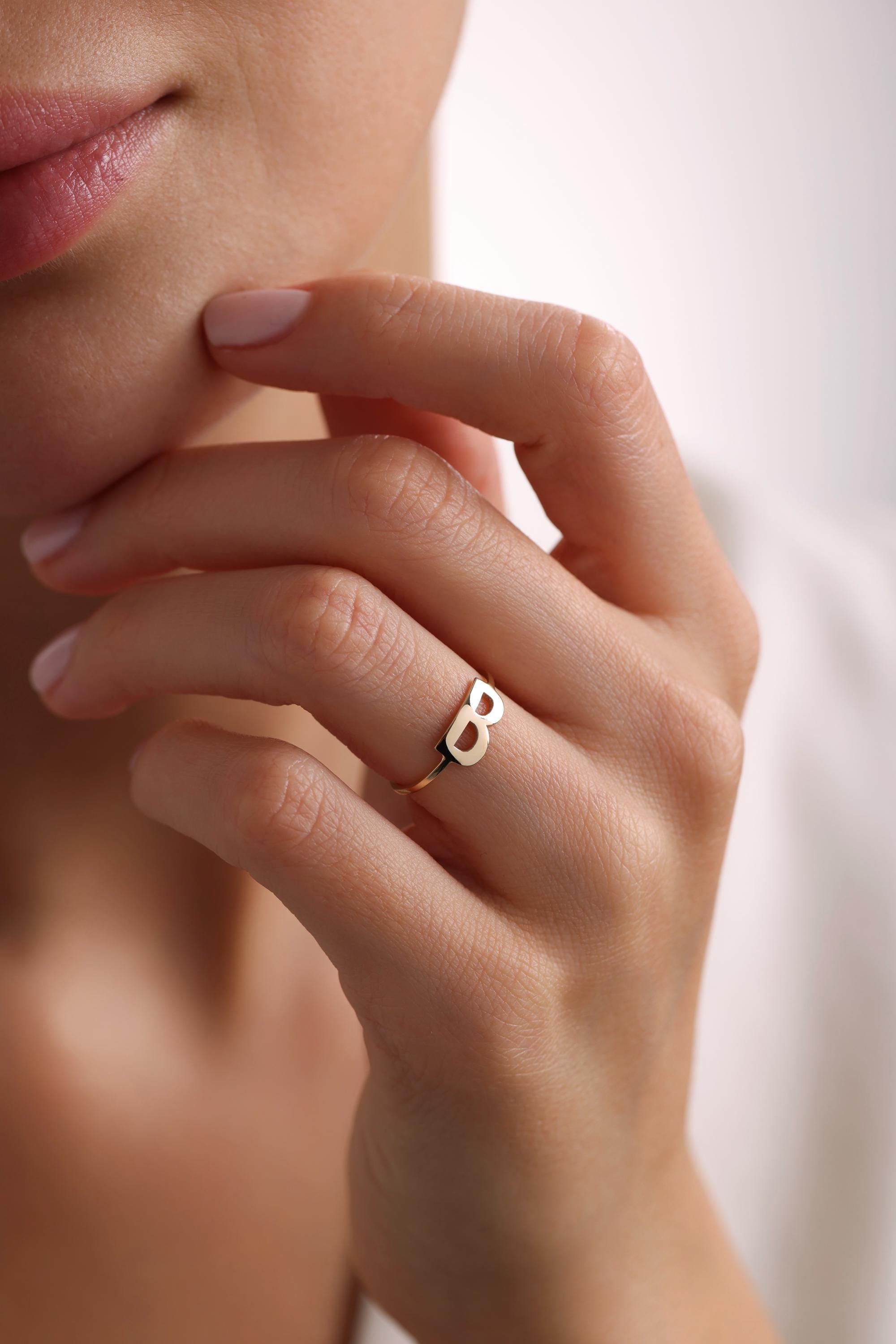 May include: A gold initial ring with the letter 'B' in a bold, modern font.