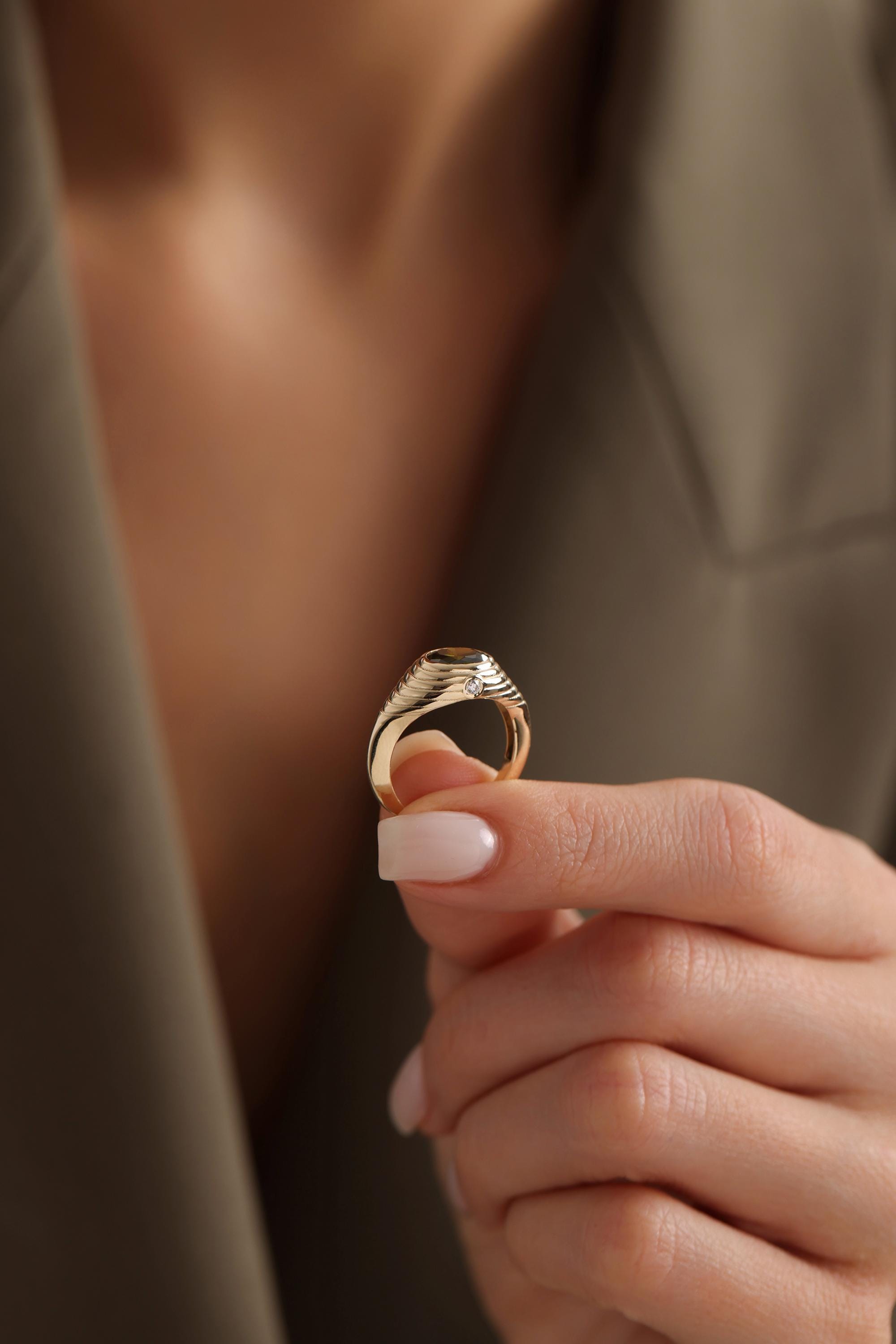 A close-up image of a person's hand holding a gold ring with a unique design.