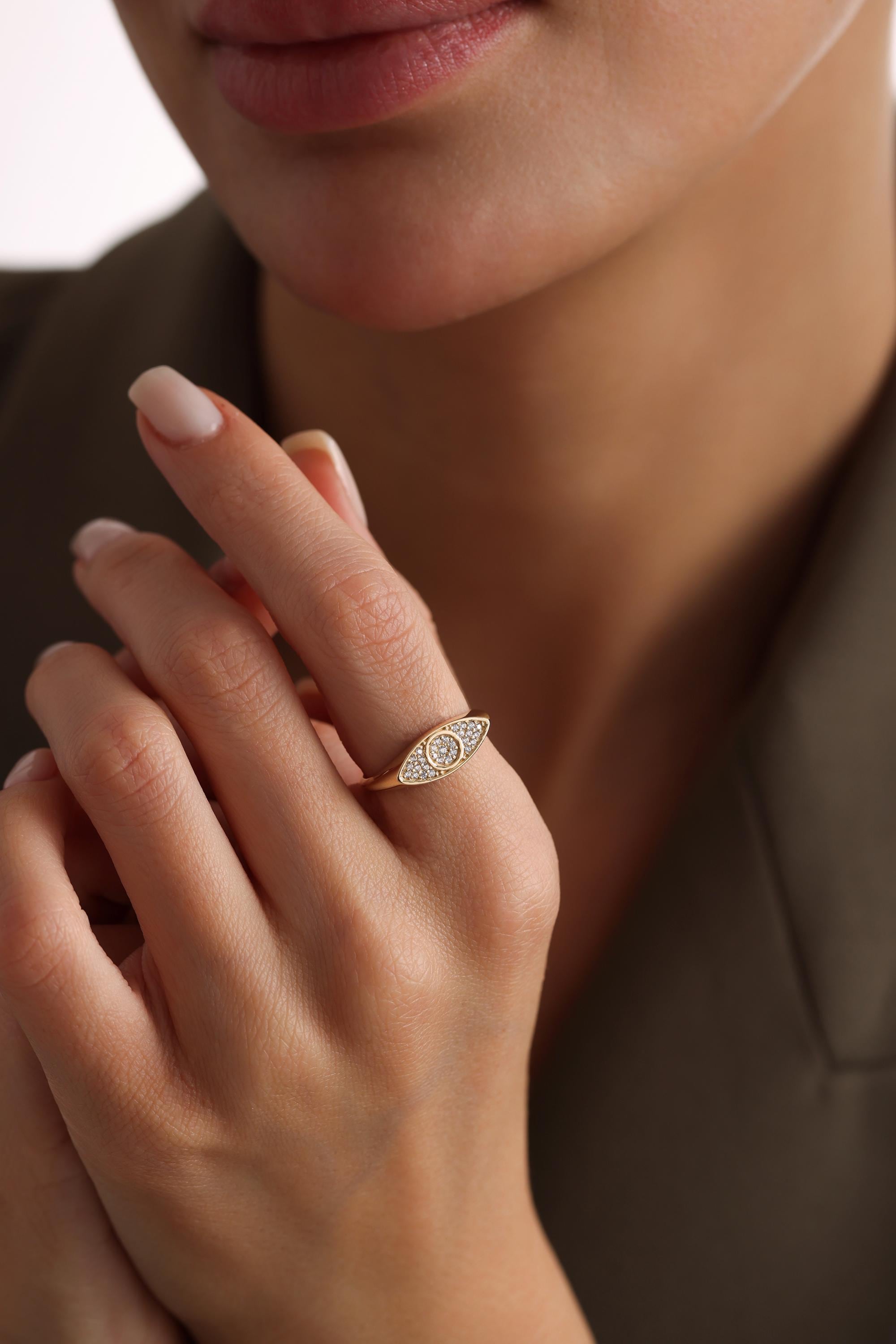 A close-up of a person's hand wearing a gold ring with a diamond-encrusted design.