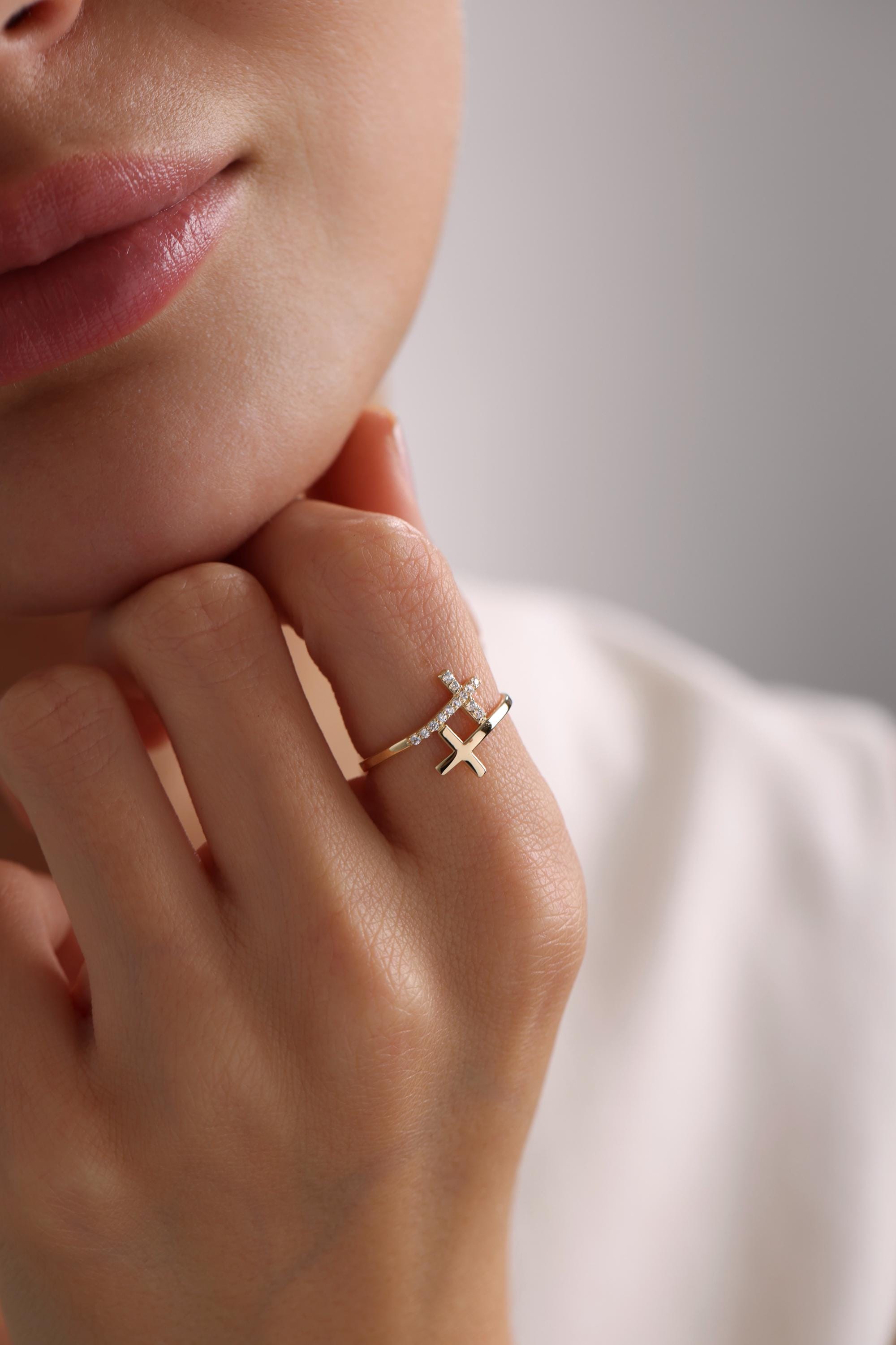 May include: A gold ring with two diamond-encrusted crosses. The crosses are set at an angle to each other.