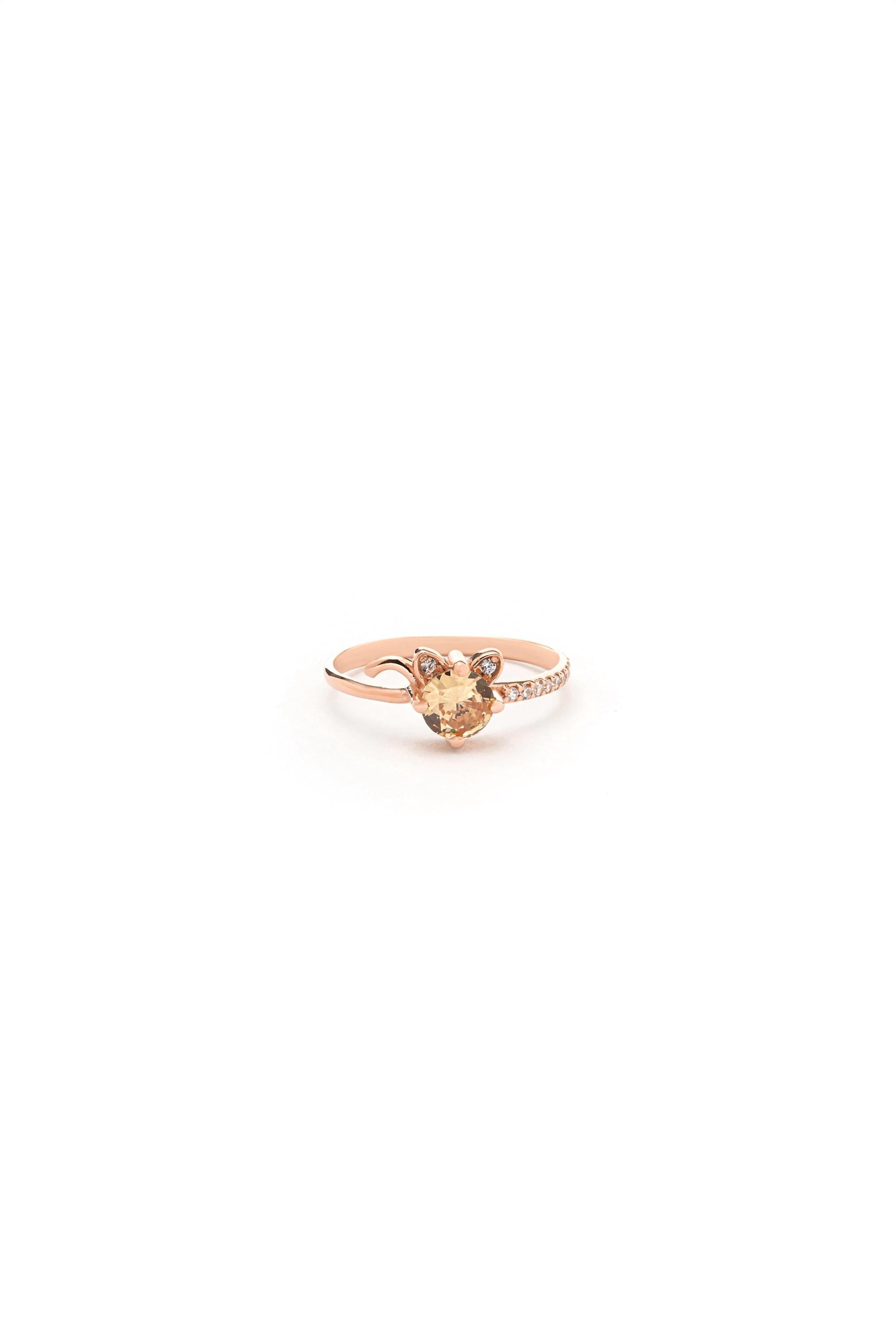 A single rose gold ring with a large, clear gemstone set in the center.