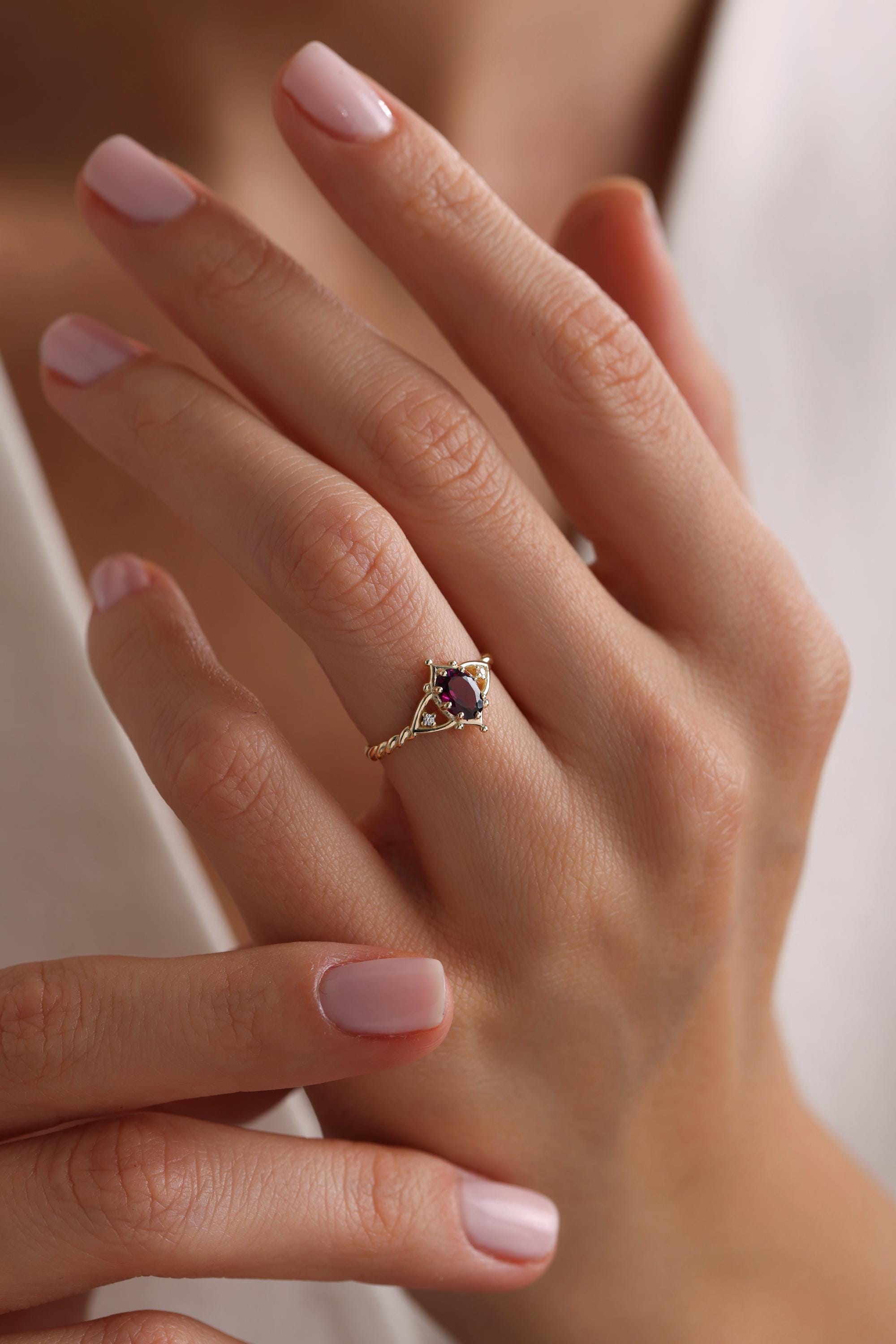 May include: A gold ring with a purple oval gemstone set in a delicate filigree design.
