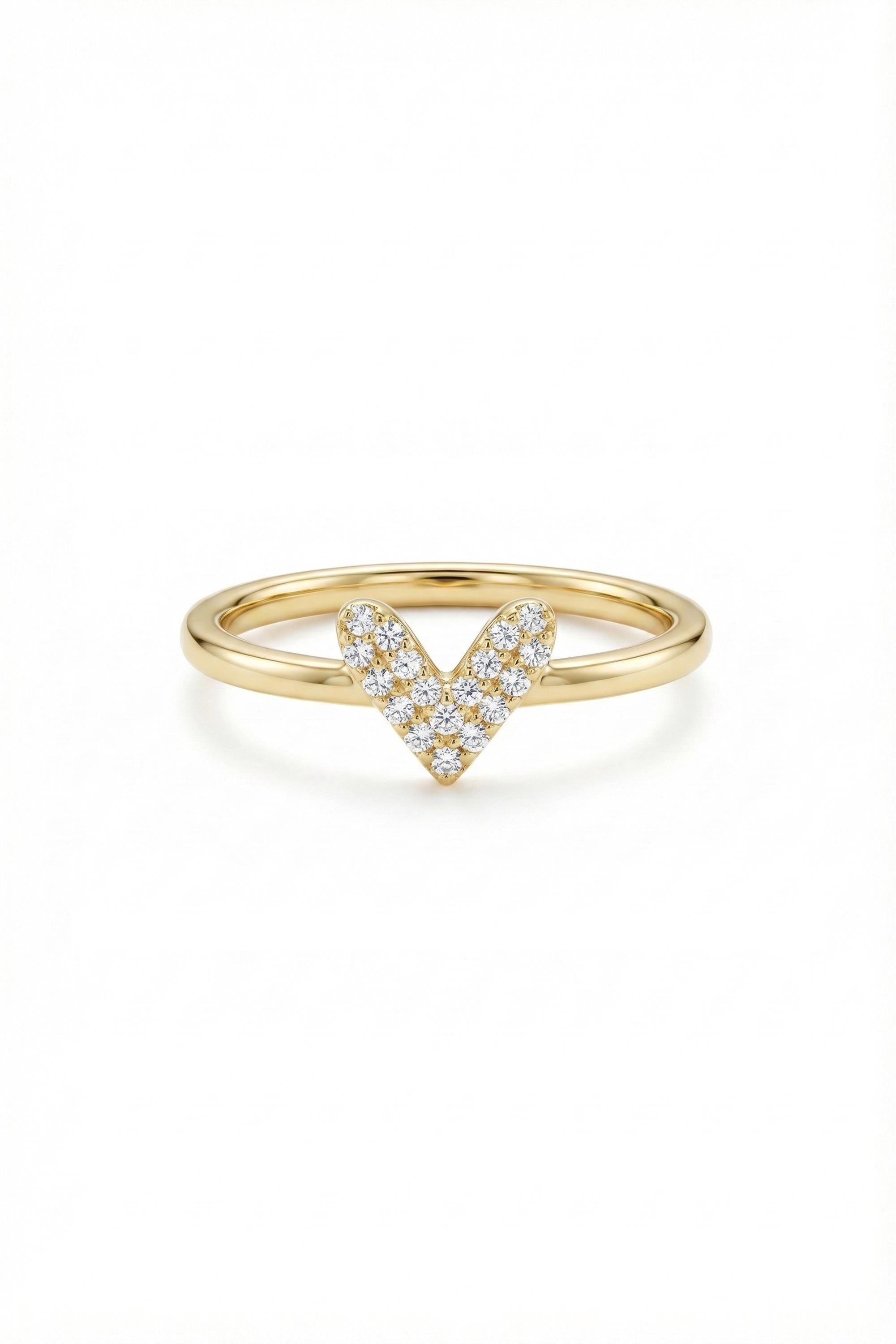 May include: A gold ring with a heart-shaped design. The heart is formed by small, sparkling diamonds set in a V-shape. The band is a smooth, polished gold. The ring is set against a white background.