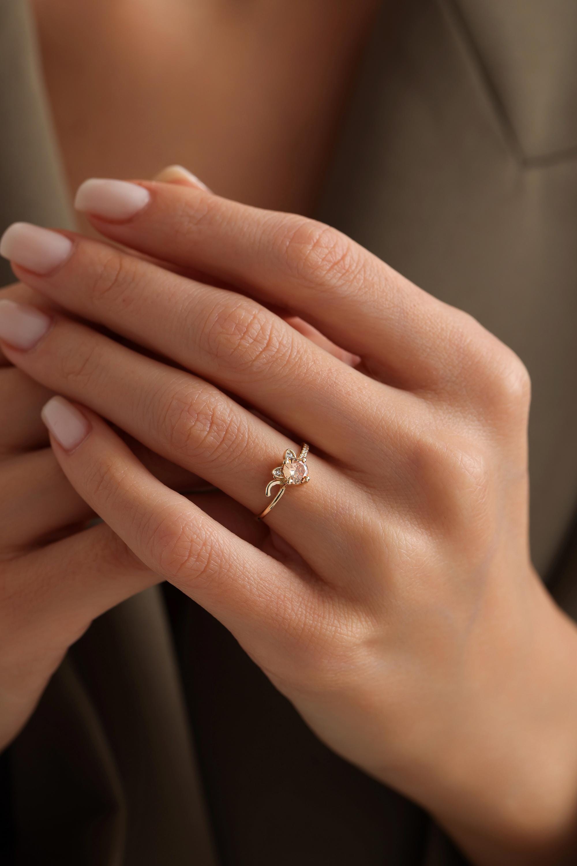 A close-up of a person's hand wearing a gold ring with a floral design.