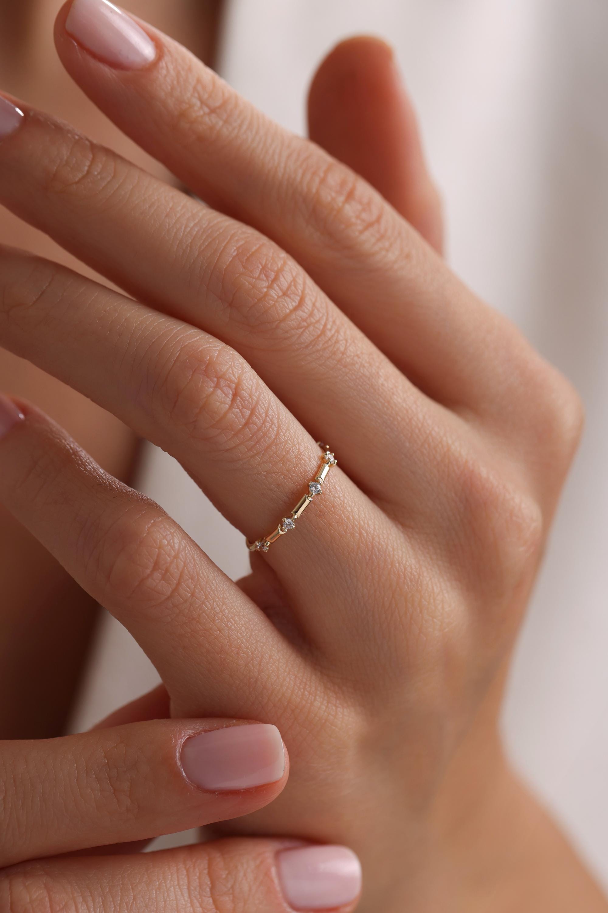 May include: A delicate gold band ring with small round diamonds set along the band.