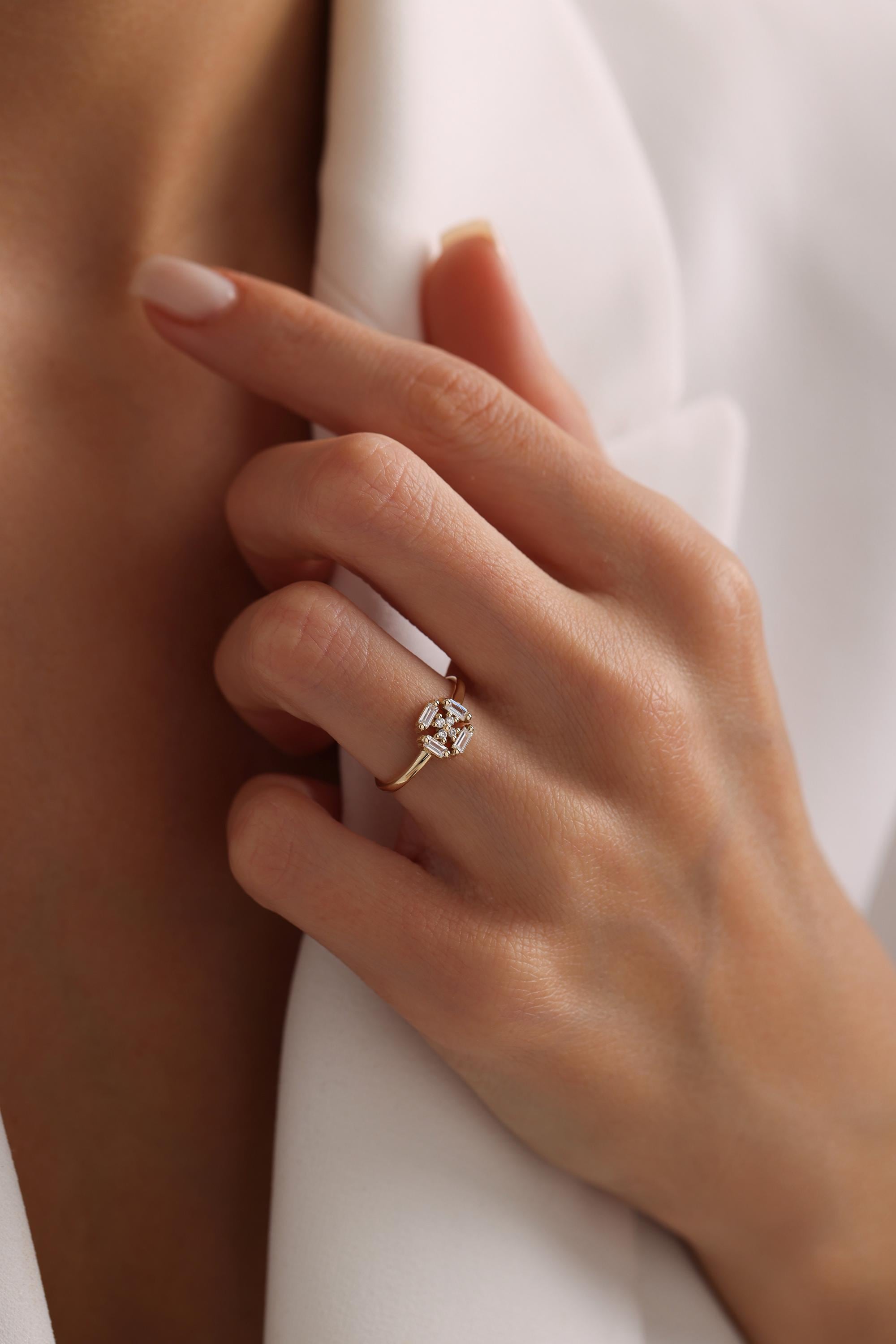 A close-up of a hand wearing a gold ring with a diamond center stone.