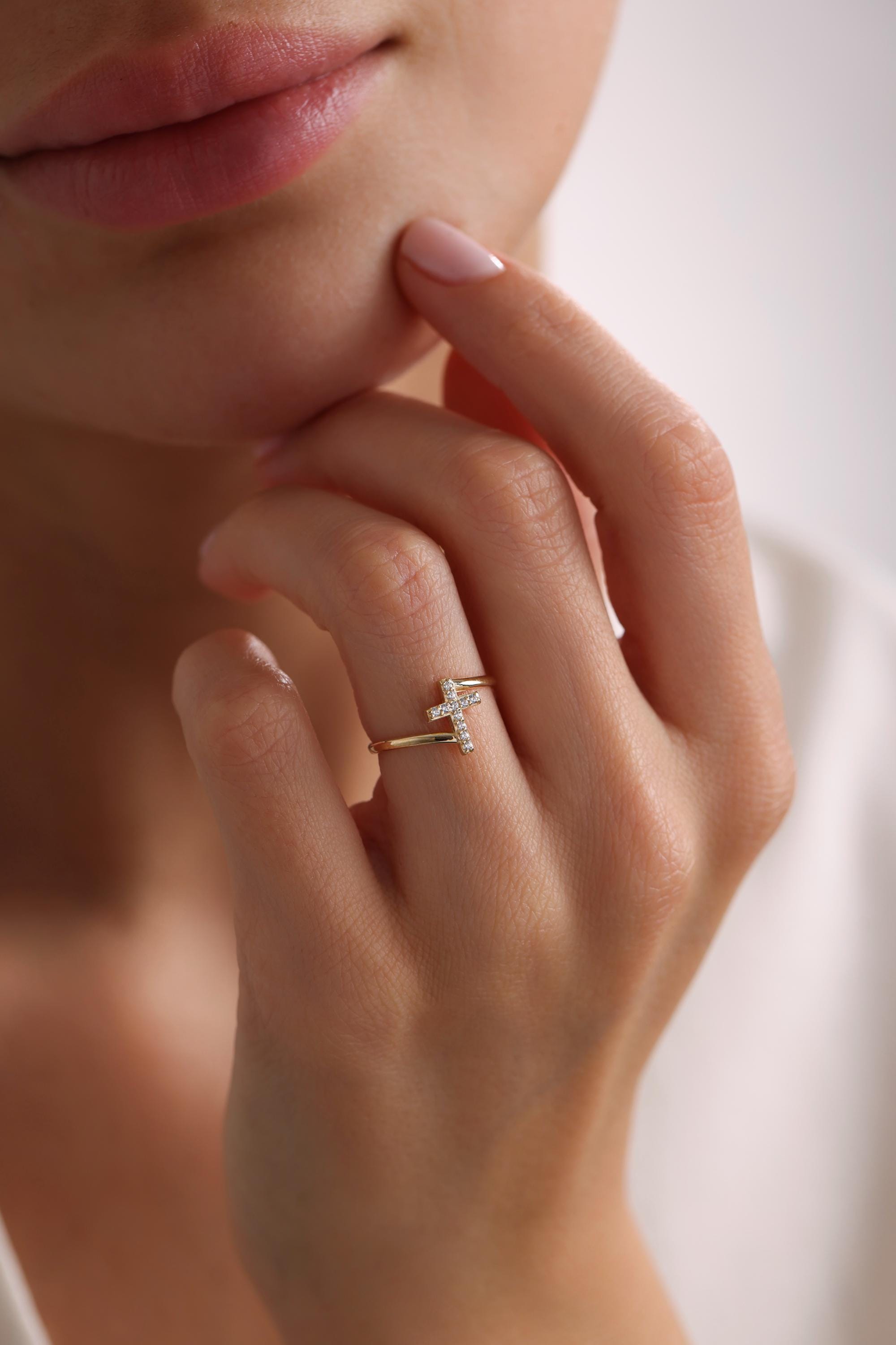 May include: A gold ring with a small, diamond-encrusted cross design.