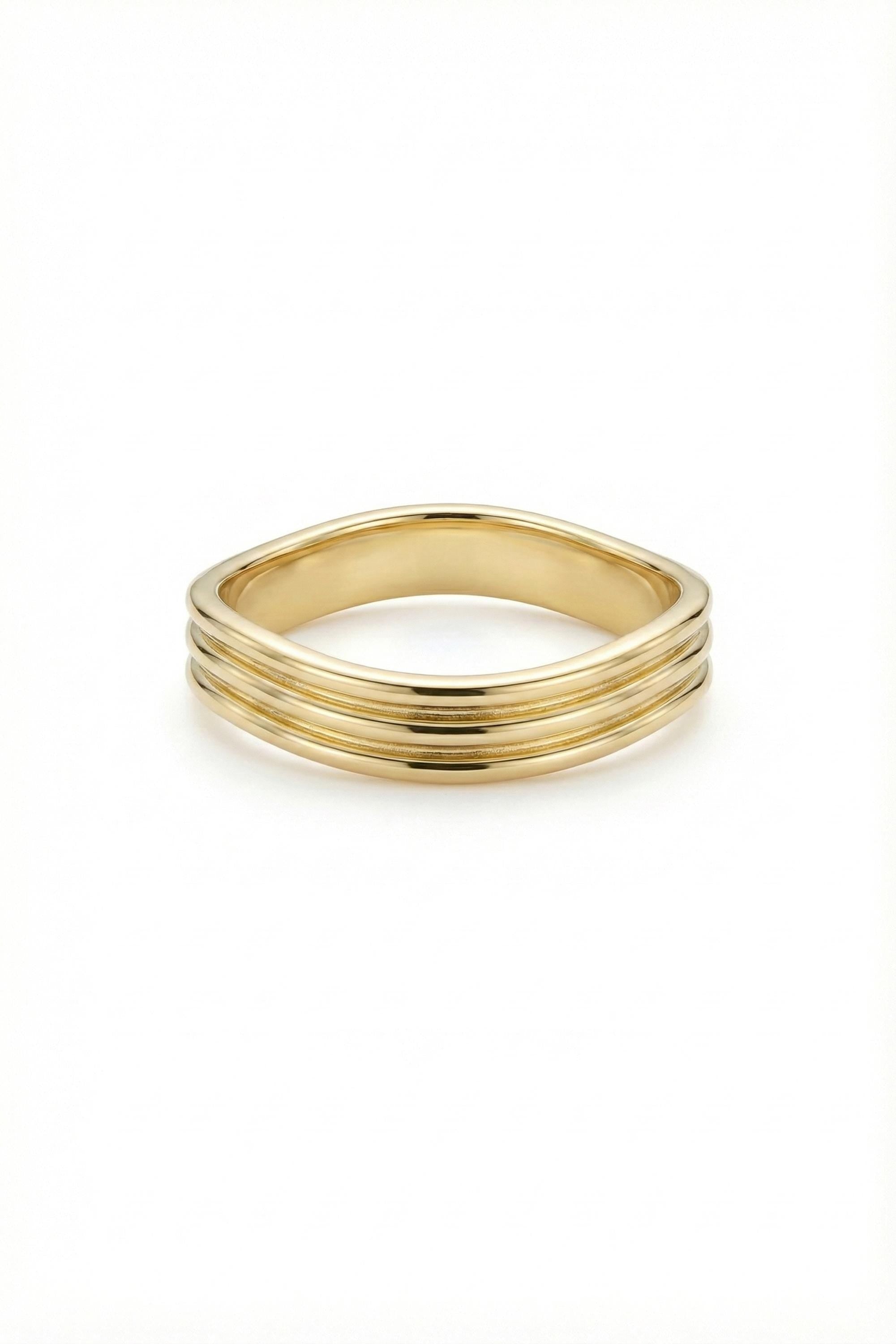 May include: A gold ring with a unique design. The ring features a series of three parallel, horizontal ridges that encircle the band. The ring has a smooth, polished finish and a slightly curved shape, creating a modern and elegant look.